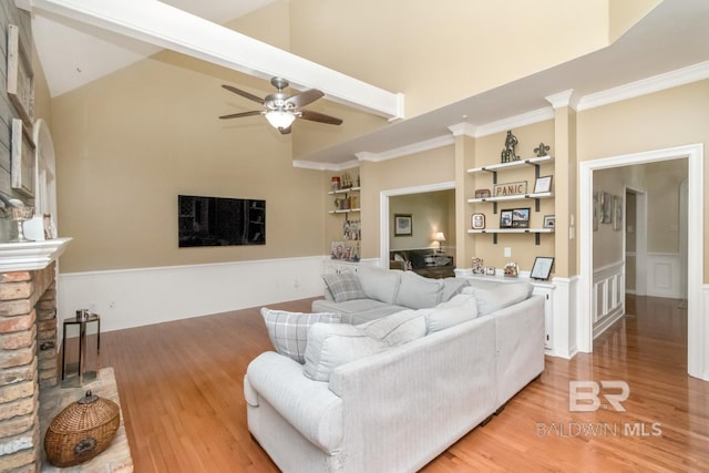 1509 Ridgeland Rd, Mobile, AL 36695 - living room featuring built in shelves, a wainscoted wall, light wood finished floors, a ceiling fan, and high vaulted ceiling
