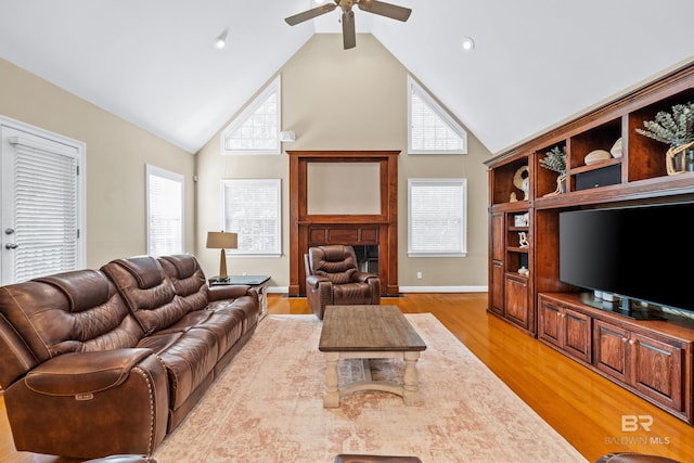 living room with light wood-type flooring, a healthy amount of sunlight, ceiling fan, and high vaulted ceiling