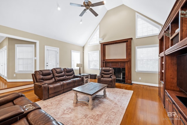 living room featuring high vaulted ceiling, wood-type flooring, ceiling fan, and a fireplace