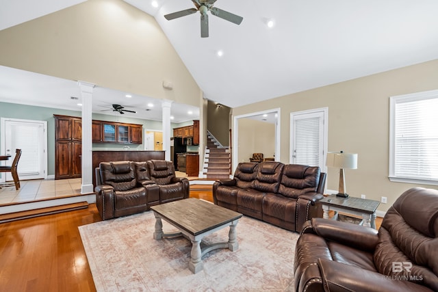 living room featuring light hardwood / wood-style flooring, decorative columns, high vaulted ceiling, and ceiling fan