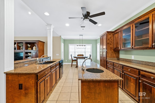 kitchen featuring pendant lighting, sink, a kitchen island with sink, and ornate columns