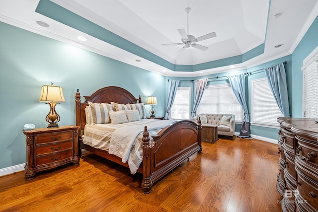 bedroom featuring ornamental molding, a tray ceiling, ceiling fan, and hardwood / wood-style flooring