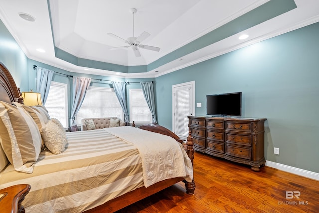 bedroom with crown molding, a tray ceiling, ceiling fan, and hardwood / wood-style flooring