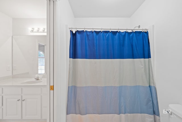 bathroom with curtained shower, vanity, and toilet