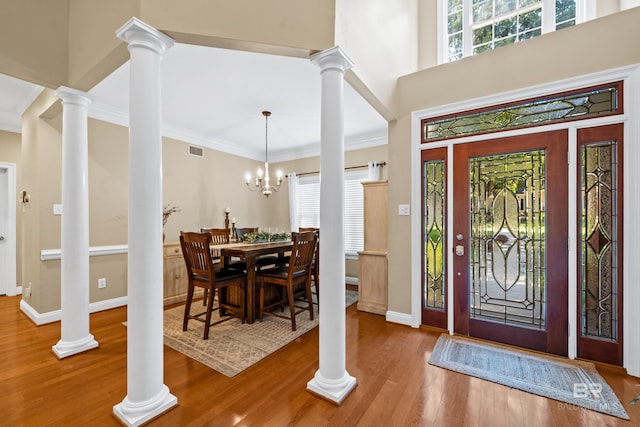 foyer featuring an inviting chandelier, hardwood / wood-style flooring, crown molding, and a towering ceiling