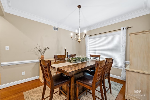 dining area featuring ornamental molding, a notable chandelier, and hardwood / wood-style floors