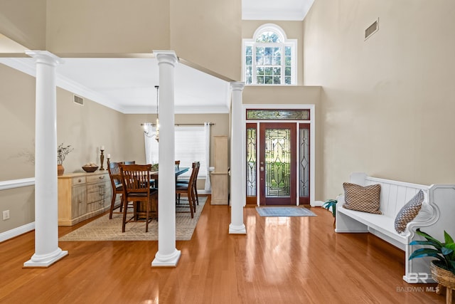 entryway with crown molding, a towering ceiling, an inviting chandelier, and hardwood / wood-style flooring