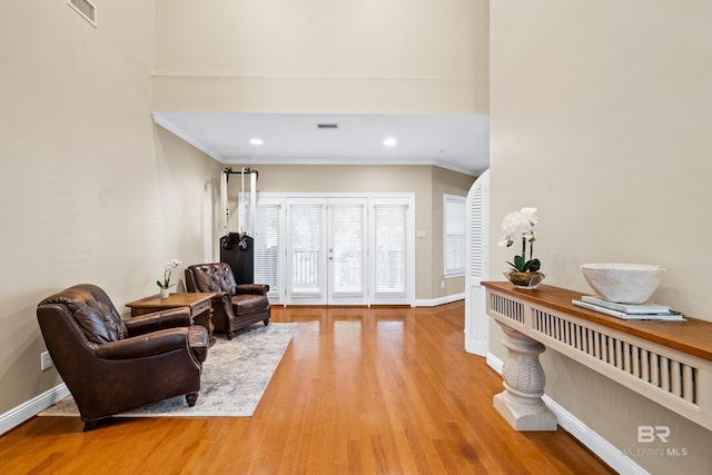 sitting room with light wood-type flooring and ornamental molding