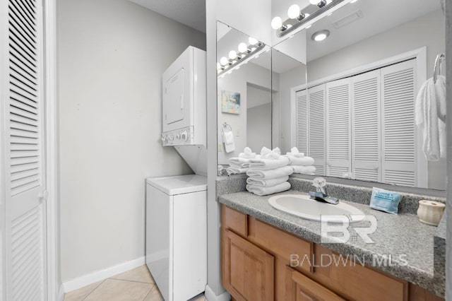 bathroom with a closet, tile patterned flooring, stacked washer and clothes dryer, and visible vents