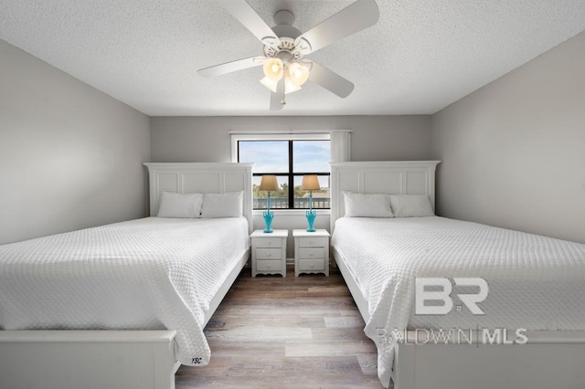 bedroom with a textured ceiling, wood finished floors, and a ceiling fan