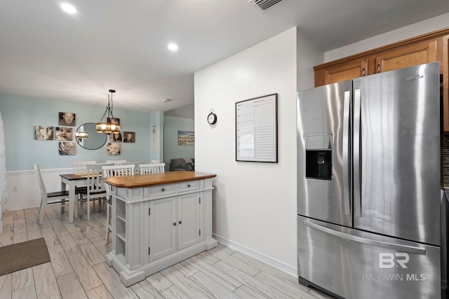 kitchen featuring wood finish floors, open shelves, recessed lighting, stainless steel fridge, and butcher block counters