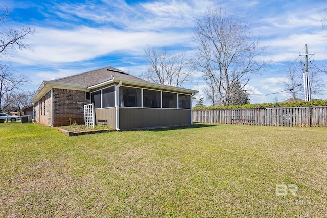 back of property featuring brick siding, fence, central air condition unit, a lawn, and a sunroom