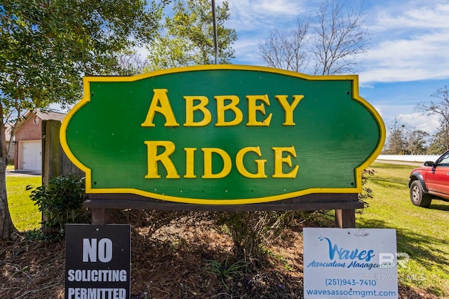 community / neighborhood sign featuring a garage and a yard