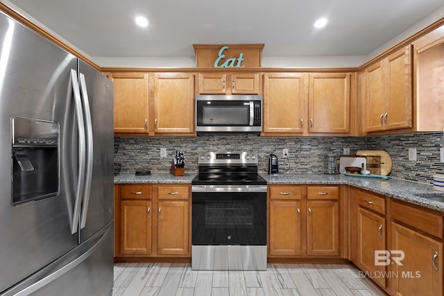 kitchen featuring dark stone countertops, tasteful backsplash, appliances with stainless steel finishes, and brown cabinets