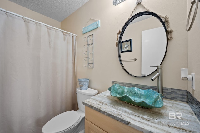 bathroom with vanity, toilet, and a textured ceiling