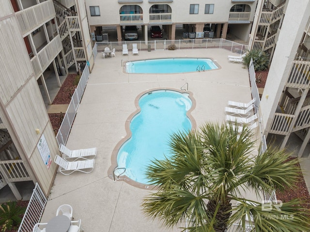 community pool with fence and a patio area