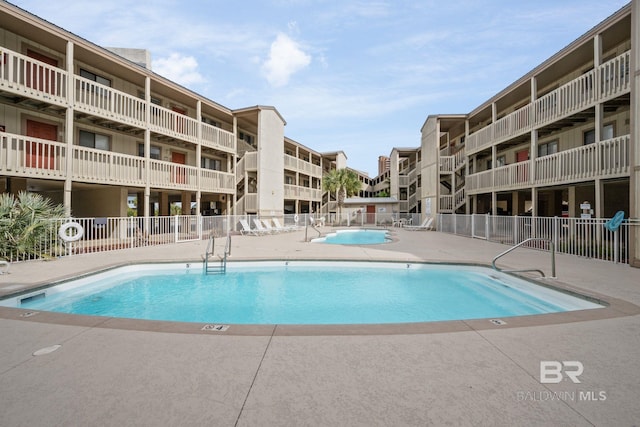 community pool with fence and a patio area