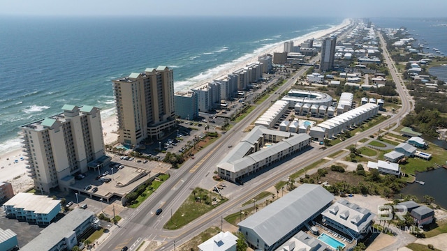aerial view of property and surrounding area featuring waterfront with a beach and nearby urban area