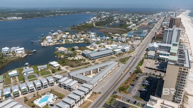 aerial view of property and surrounding area featuring a large body of water, a pool area, and nearby urban area