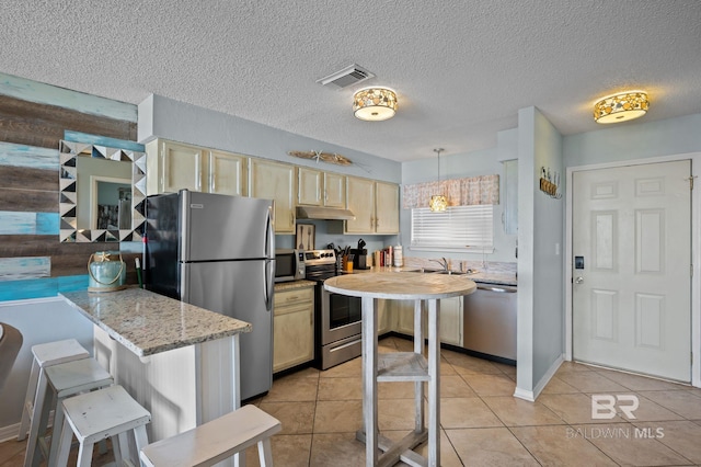 kitchen featuring stainless steel appliances, under cabinet range hood, a sink, light tile patterned floors, and light brown cabinetry