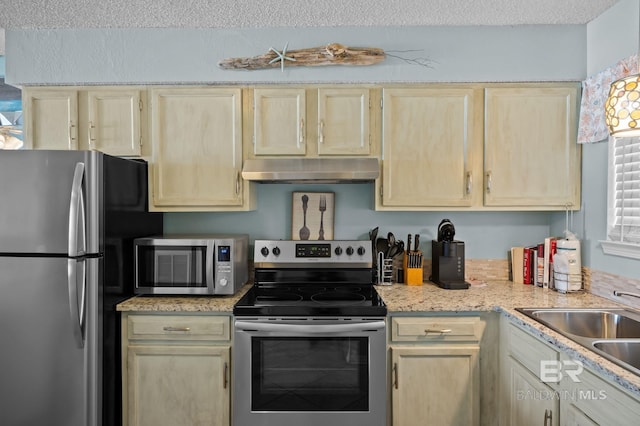 kitchen featuring appliances with stainless steel finishes, under cabinet range hood, light brown cabinetry, light countertops, and a sink