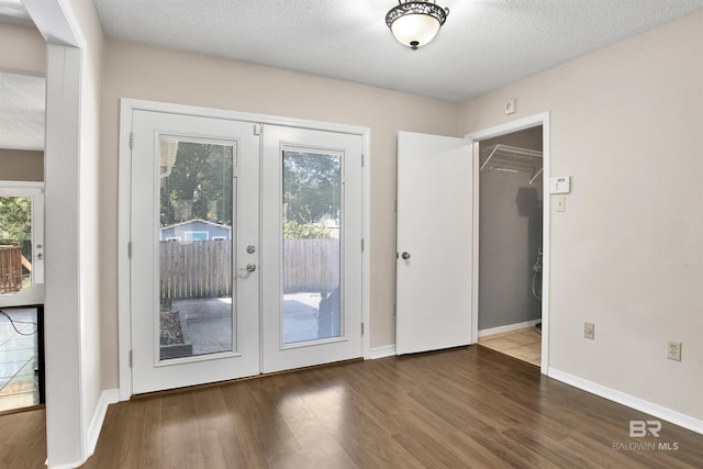 doorway with a healthy amount of sunlight, a textured ceiling, dark hardwood / wood-style flooring, and french doors