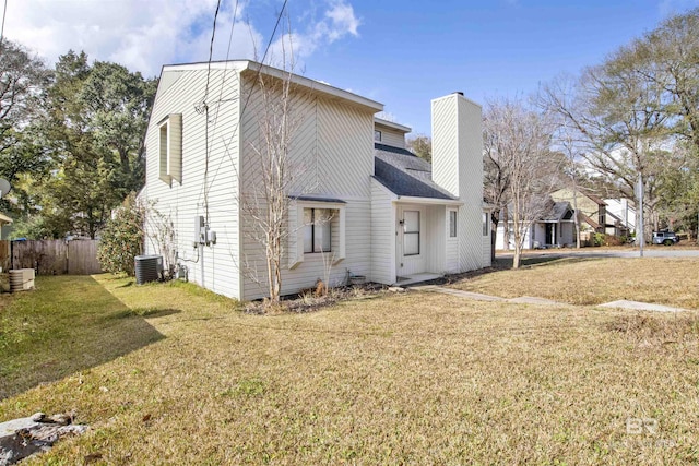 view of side of home with central AC and a lawn