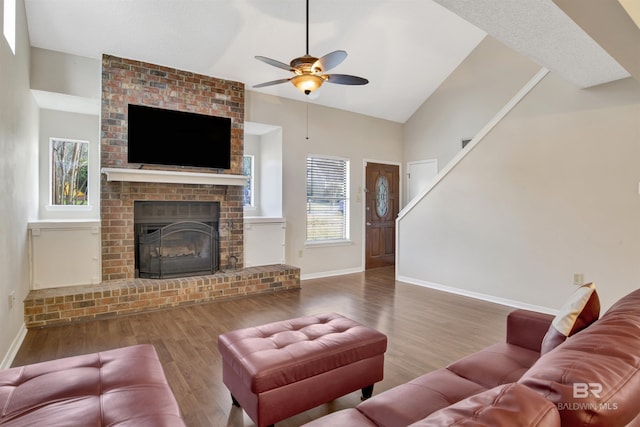 living room with dark wood-type flooring, ceiling fan, high vaulted ceiling, and a brick fireplace