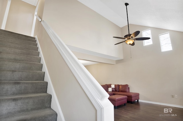 stairway featuring ceiling fan, wood-type flooring, and high vaulted ceiling