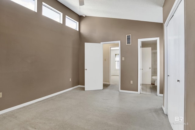 unfurnished bedroom featuring ceiling fan, connected bathroom, light carpet, and high vaulted ceiling