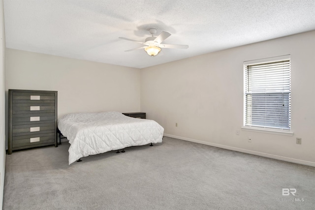 carpeted bedroom with ceiling fan and a textured ceiling