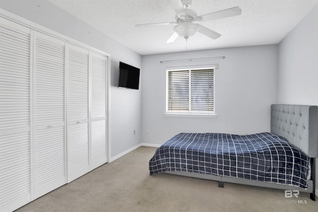 bedroom with ceiling fan, a closet, a textured ceiling, and carpet