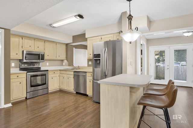 kitchen featuring dark hardwood / wood-style flooring, hanging light fixtures, stainless steel appliances, and sink