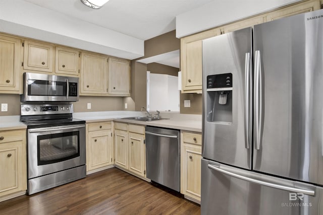 kitchen with stainless steel appliances, sink, dark wood-type flooring, and light brown cabinetry