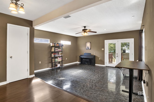 interior space featuring ceiling fan with notable chandelier, a textured ceiling, and french doors