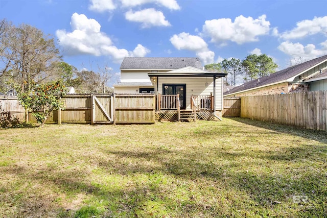 back of property with a wooden deck and a lawn