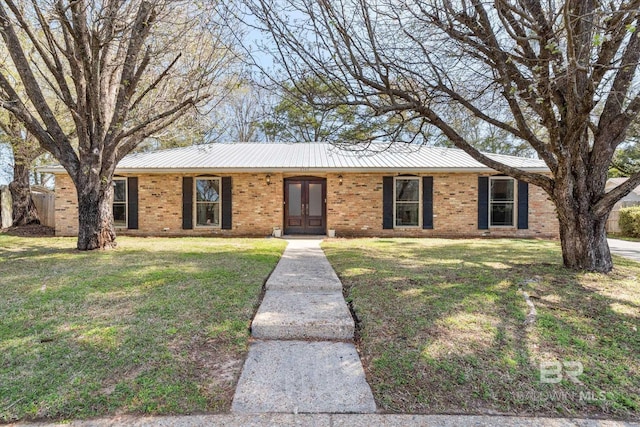 ranch-style house featuring metal roof, brick siding, and a front lawn