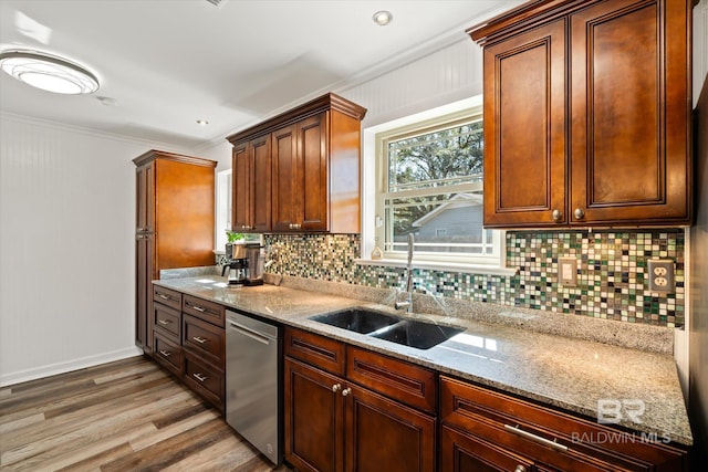 kitchen featuring light wood finished floors, tasteful backsplash, dishwasher, light stone counters, and a sink