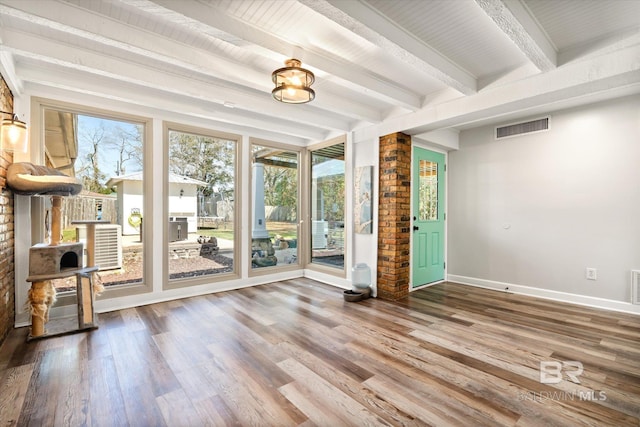 unfurnished room with visible vents, baseboards, beam ceiling, and wood finished floors