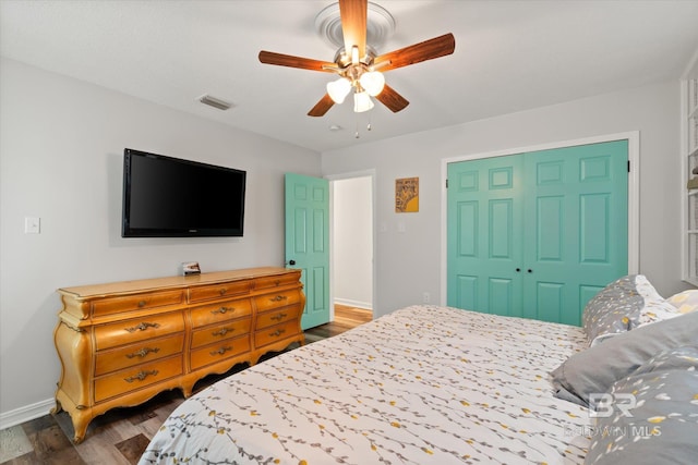 bedroom featuring ceiling fan, visible vents, baseboards, and wood finished floors