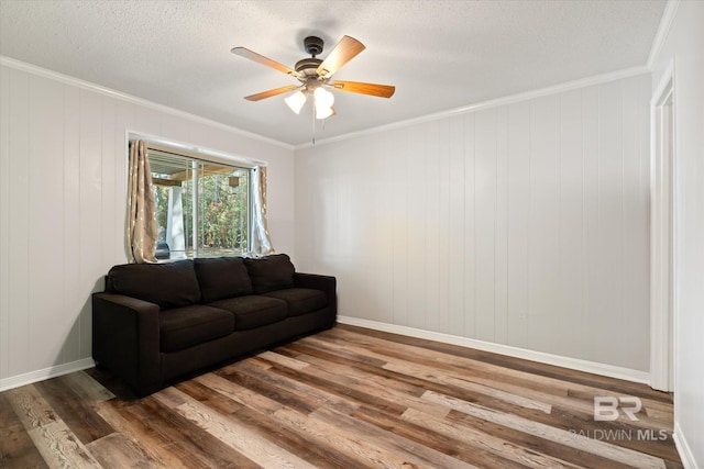 living room with ceiling fan, wood finished floors, a textured ceiling, and ornamental molding