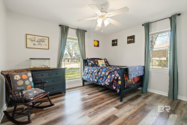 bedroom featuring baseboards, wood finished floors, and a ceiling fan