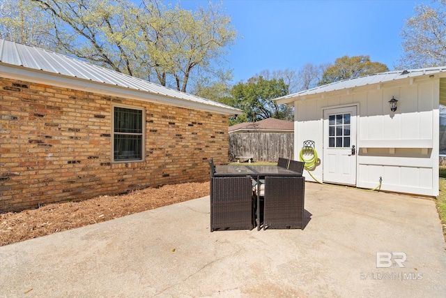 view of patio / terrace featuring an outbuilding, outdoor dining area, and fence