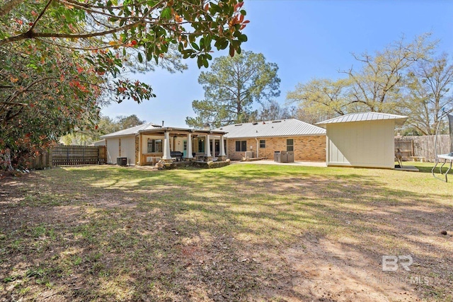 rear view of house featuring a patio, a fenced backyard, a shed, a yard, and an outdoor structure