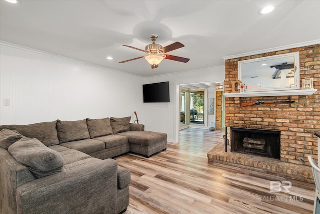 living room with a ceiling fan, recessed lighting, crown molding, light wood finished floors, and a brick fireplace