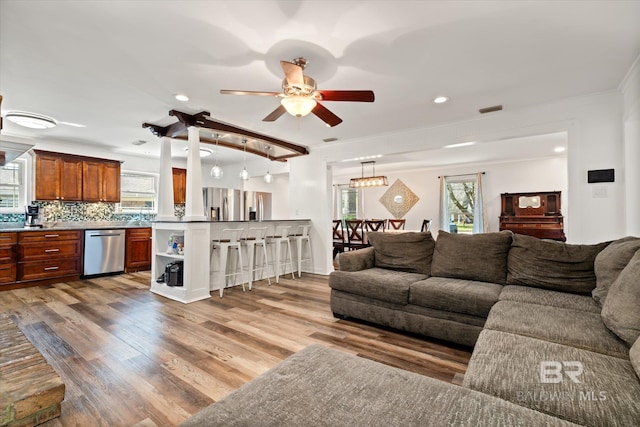 living room featuring light wood-type flooring, visible vents, ornamental molding, recessed lighting, and ceiling fan