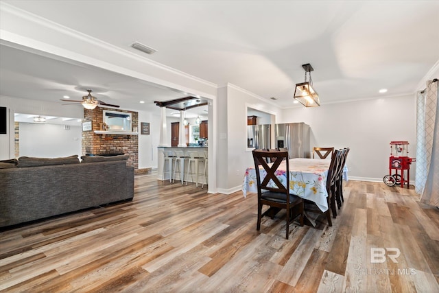 dining space featuring baseboards, wood finished floors, visible vents, and ornamental molding