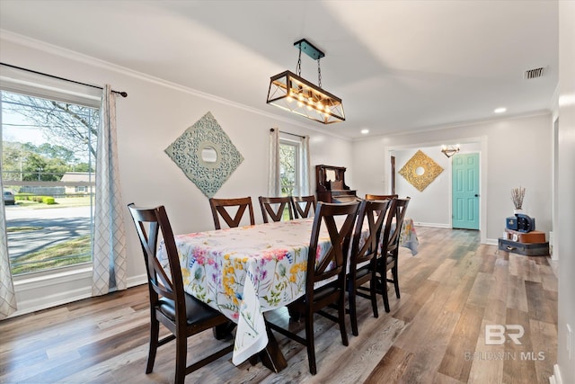 dining area featuring wood finished floors, visible vents, and ornamental molding