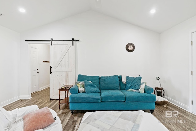 living area featuring a barn door, wood finished floors, baseboards, and vaulted ceiling