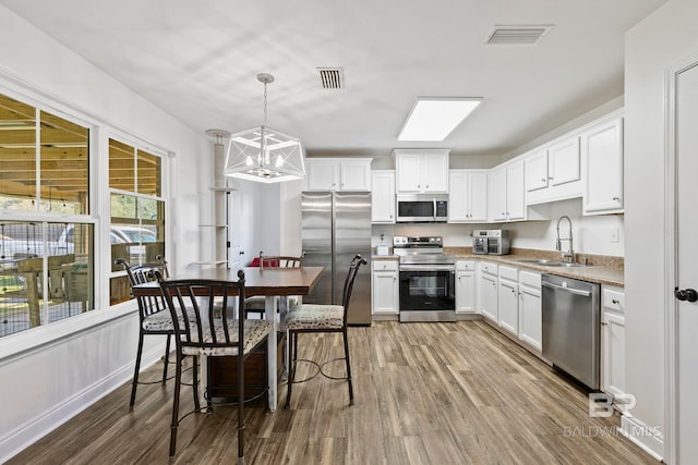 kitchen with dark wood-style floors, visible vents, a sink, appliances with stainless steel finishes, and white cabinetry